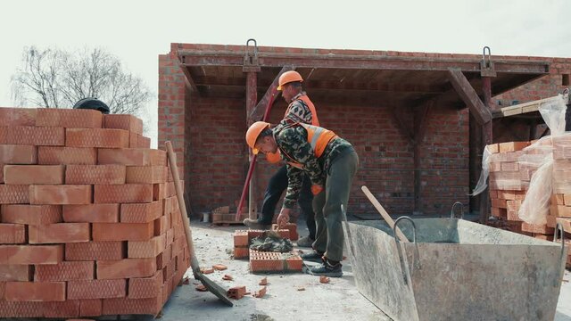 Two builders laying a brick wall on the construction of a multi-storey building.