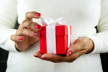 Girl holding present decorated with red paper and white ribbon. Concept sales, shopping, christmas holidays, Valentine's Day and birthday.