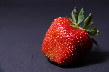 horizontally oriented background image, isolated ripe fresh strawberry berry on dark gray background 
