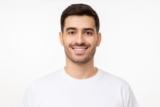 Portrait of young handsome smiling man wearing white t-shirt, isolated on gray background