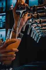 bartender hand at beer tap pouring a draught beer in glass serving in a restaurant or pub