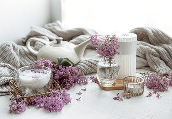 Spring home still life with a cup of milk and lilac flowers.