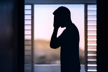 Sad and emotional young man indoors silhouette. 