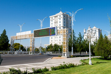 Overhead road sign and lamp posts ornamented at Ashgabat, Turkmenistan. Gold decoration in upscale area with white marble buildings in Central Asia. - obrazy, fototapety, plakaty