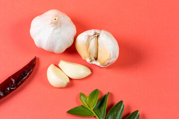 A cluster of Spices laid on the side of a Reddish Pink background.