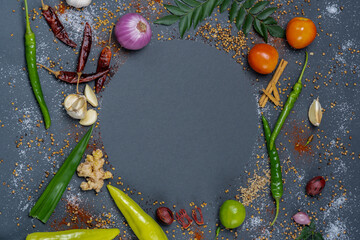 Circular pattern of Chillies, Garlic, Ginger, Salt, Mustard, Curry leaves, Onion, Tomatoes, Capsicum, Fenugreek, Dried chillies and Cinnamon.