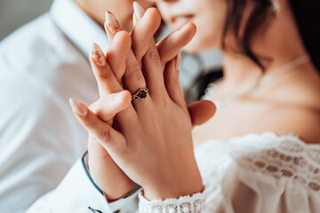 Bride and groom puts a wedding ring on finger. Husband and wife two lovers near window celebrate their wedding engagement. Procreation romantic newlyweds indoor, copy space.