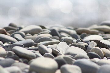 Pebble stones on sea shore blurred out of focus lights natural background.
