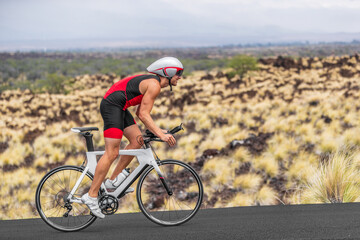 Cycling sport athlete man biking on triathlon bike. Fit male cyclist on professional triathlon bicycle wearing time trial helmet for iron man race exercising in Kailua Kona, Big Island, Hawaii, USA.