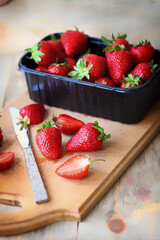 Strawberry slices on a wooden board. Knife. Tray with strawberries.