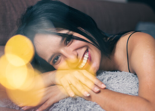 mujer latina sonriendo sobre un coj&iacute;n con luz c&aacute;lida. 