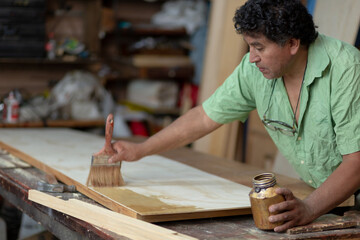 Mexican woodworker, carpenter varnishing on his workshop