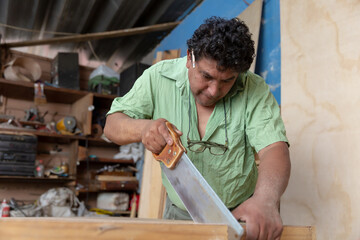 Mexican carpenter cutting wood with saw