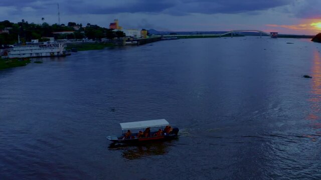 A small boat crossing the Rio Paraguay in Corumba, Brazil at sunset - aerial view
