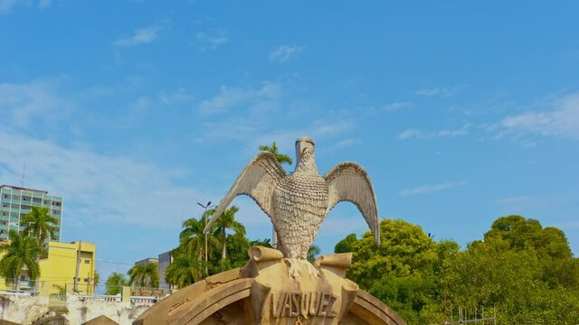 Statue of a bird on a traffic circle in the historic city or Corumba, Brazil - orbiting view of the sky and cloud