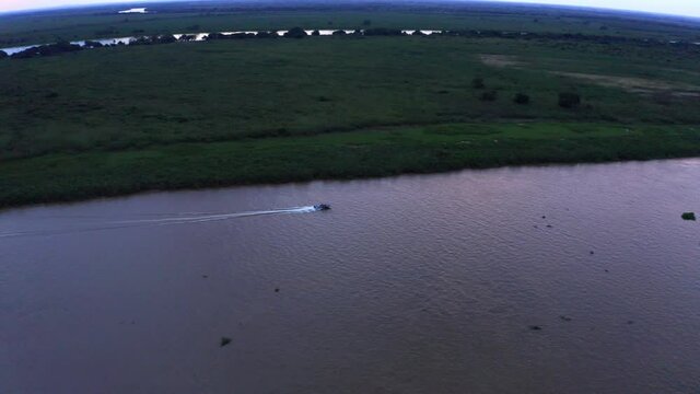 A speedboat on the Rio Paraguay River at sunset with the colors from the sky reflecting on the water