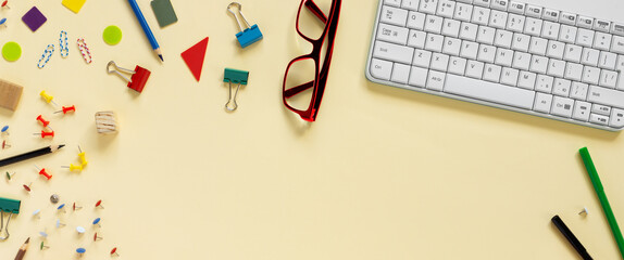 School and office supplies border with keyboard on beige paper background. Multicolored pencils, paints, plasticine, abacus, pushpins and other school accessories