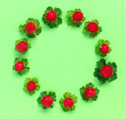 Round garland  from  leaves and berries, on green paper background, flat lay, top view. The concept of summer, spring, Mother's Day.