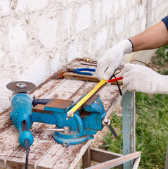 Worker makes repairs  with electric tools  hammer and  pliers in backyard of house in outdoor.