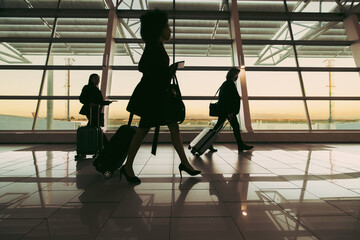 Silhouette of people walking at airport terminal - obrazy, fototapety, plakaty