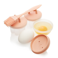 Set of heat resistant silicone molds for poached egg, basting brush and fresh raw eggs isolated on white background.