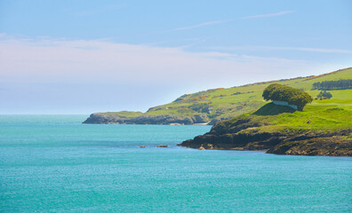Fototapeta premium High cliff on tropical beach. Tropical nature. Beautiful blue sea water and green tropics of shoreline. Scenic sea landscape Ireland.