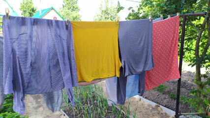 Wet colored laundry hanging on a clothesline in the open air. Drying clothes on the clothesline.