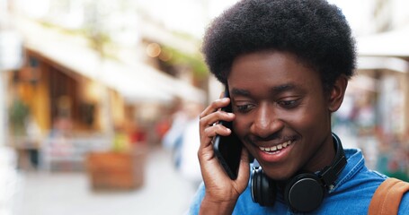 Portrait of the attractive young man talking at the smartphone outdoors while using mobile phone for making call at the street with blurred background. People and technologies concept