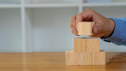 Hand arrangement of wooden blocks on a wooden table. Business Ideas for Successful Growth Wooden cubes or blocks for white copy space and text input.