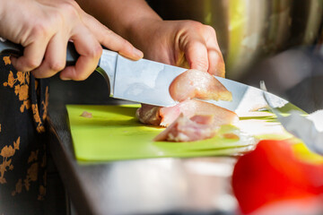 A person cutting chicken meat to prepare it for cooking