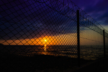 wire fence in calm sunset and ocean view 