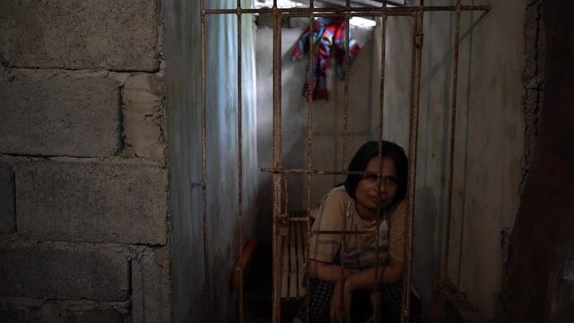 Schizophrenic Adult Woman Sitting Behind Metal Bars Suffering From Depression and Anxiety in The Philippines. 
