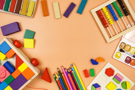 Colorful cubes, paints, pencils, blocks, modeling clay on orange background. Interesting math, games for preschool for kids. Education, back to school concept