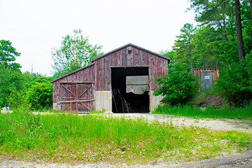 Old barnhouse in dire need of repair on an unpaved back road in rural Maine