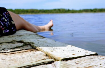 Close-up of a woman's legs on a wooden pier. Lake in the background