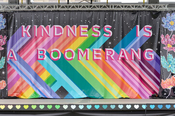 Kindness is a boomerang poster on a stage celebrating the pride month with colorful rainbow flag...