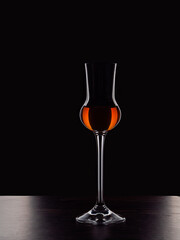 shaped grappa glass with liquid on a dark background