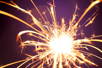 Close up of burning sparkler firework with lots of hot glowing embers exploding. For New Years or 4th of July celebration.