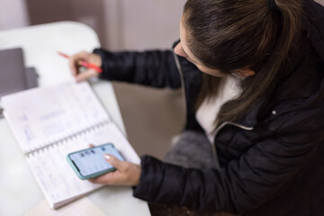 Mulher trabalhando em casa, usando lápis, caderno e celular. Fazendo anotações se comunicando...