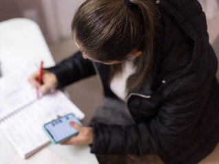 Mulher trabalhando em casa, usando lápis, caderno e celular. Fazendo anotações se comunicando...