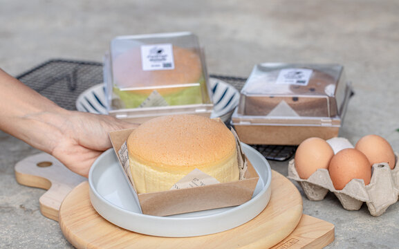 Lady hold Taiwanese castella cake on white plate with wooden board.