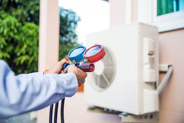 Close-up engineer using measuring manifold gauge for filling industrial air conditioner after cleaner and checking for maintenance outdoor air compressor unit.