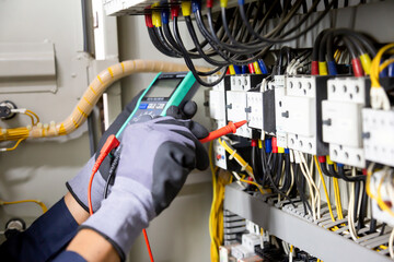 Electrician engineer tests electrical installations and wires on relay protection system. Adjustment of scheme of automation and control of electrical equipment.