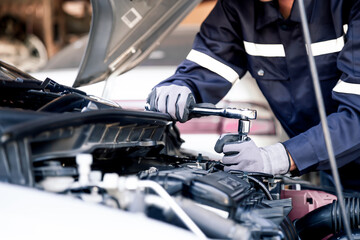 Professional mechanic working on the engine of the car in the garage. Car repair service. The...