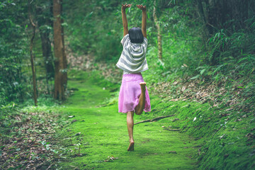 Happy little girl bare feet dance on green moss in fairy forest  trail