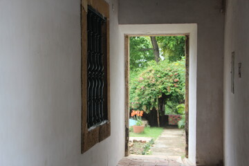 Fototapeta na wymiar A barred window near the exit to the garden of a house in the colonial town of Olinda, Brazil.