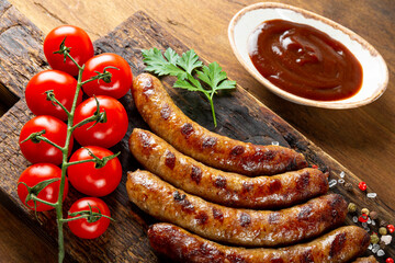  Grilled minced beef and pork sausages with barbecue sauce on wooden board close up