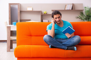 Young male student sitting on the orange sofa