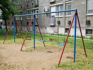 Fototapeta na wymiar Swings at the playground next to an apartment building