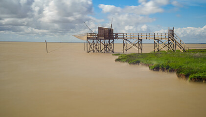 Calm brackish water of Gironde estuary, France with fishing hut on coastline of Charente-Maritime